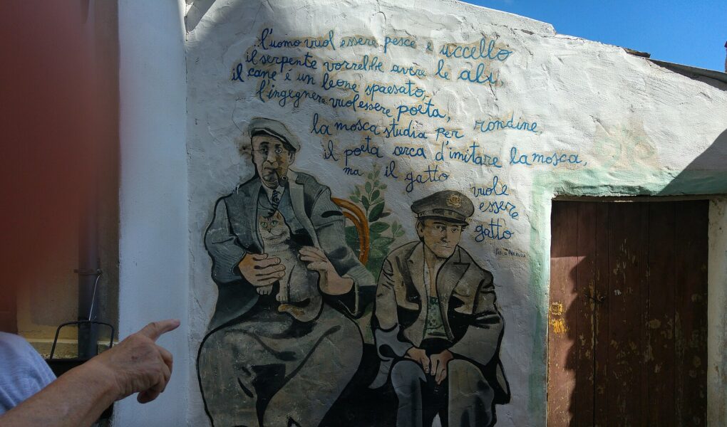 Murale di Orgosolo con due uomini e versi dipinti su un muro bianco