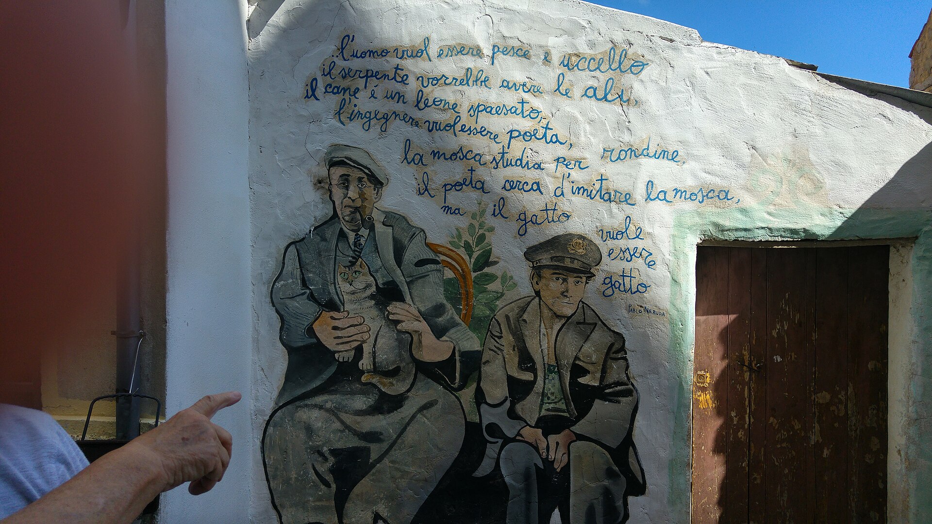 Murale di Orgosolo con due uomini e versi dipinti su un muro bianco
