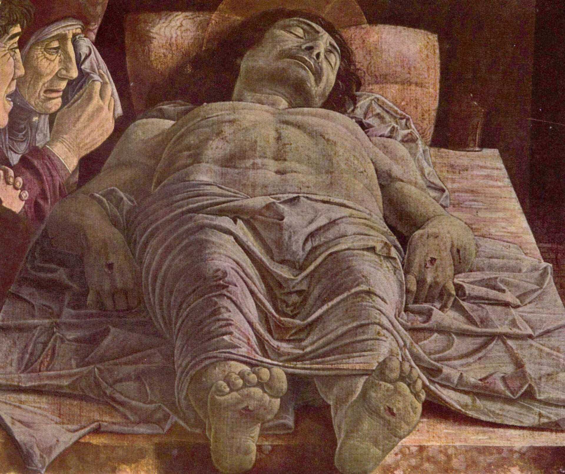 Cristo morto di Andrea Mantegna: il corpo di Cristo disteso in scorcio sulla pietra, con i piedi verso chi guarda e tre dolenti a sinistra